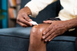 © WESTOCK - Close up of unrecognizable old man applying ointment cream for joint knee pain at home - concept of treatment or therapy for osteoarthritis and knee sprain