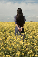Woman In Classic Blue Dress Standing In Yellow Field Of Rapeseed Flowers In Spring