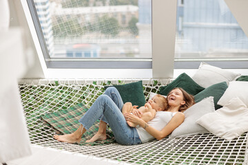 Happy young mother and child on a mesh hammock