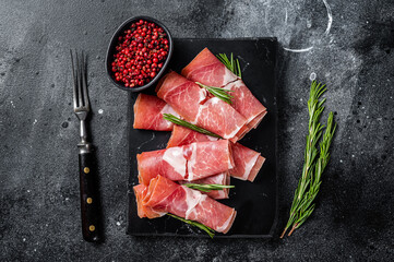 Traditional Spanish Jamon Serrano ham on marble board. Black background. Top view