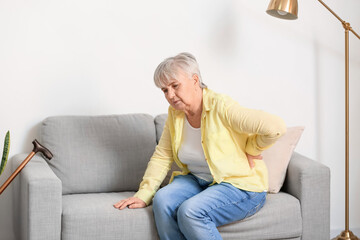 Sticker - Senior woman suffering from back pain on sofa at home