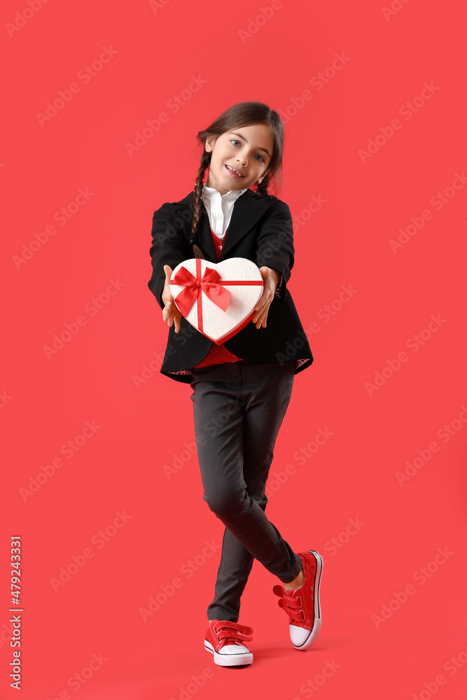 Funny little girl with gift on color background. Valentine's Day celebration