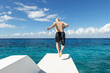 © Mat Hayward - Shirtless man runs on diving platform to jump into vibrant blue Caribbean ocean water on the tropical island of Cozumel, Mexico