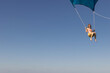 © Mat Hayward - Girl flying over the Caribbean sea during fun activity with a spinnaker parachute ride. The wind is lifting her into the air as she holds on to the kite.