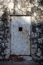 Old Fading Door With Peeling And Cracked Paint Surrounded By Ancient Brick Decaying From The Weather