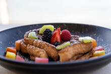 A Plate Of French Toast Topped With Fresh Fruit And Syrup For Breakfast 