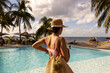 © Mat Hayward - Beautiful woman with floppy hat wearing swimsuit near a tropical island resort swimming pool on a sunny day during her vacation in paradise.