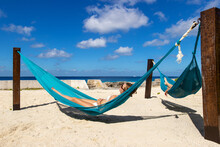 Young Woman Relaxing In Blue Hammock On A Tropical Island Beach Next To The Caribbean Sea In Mexico. 