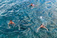 Three Women Swimming In The Blue Caribbean Sea Off The Coast Of Cozumel, Mexico In Quintana Roo For A Fun Ocean Front Vacation Activity.