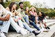 © Xavier Lorenzo - Multiracial group of young teenage student friends laughing together and having fun sitting on city street - United diverse millennial people celebrating together outside - Unity and community concept