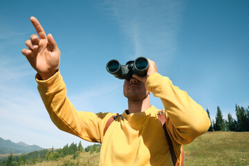 Canvas Print - Man with binoculars in mountains on sunny day