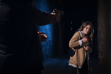 Canvas Print - Criminal threatening young woman with gun in alley at night. Self defense concept