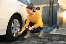Young Woman Inflating Tire At Car Service