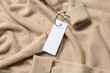 © New Africa - Blank white tags on beige sweater, top view. Space for text