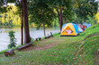 nature autumn camping cabin tents on waterfront to morning sunlight and tree with green grass and lake for family holiday vacation at pom pee campsite in khao laem national park and vajiralongkorn dam