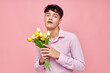 © Tatiana - A young man in a pink shirt with a bouquet of flowers gesturing with his hands isolated background unaltered