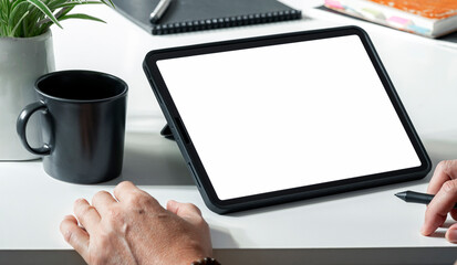 Wall Mural - Digital portable tablet computer white screen mockup. Man working on digital tablet at his desk.