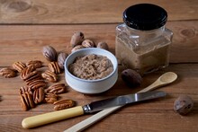Organic Pecan Butter In Bowl And Glass Jar With Raw Pecans