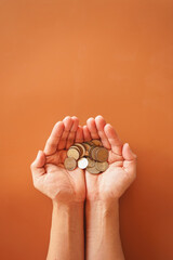 Two hand holding money coin on brown background with copy space