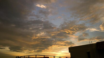 Wall Mural - View the sunset sky from the rooftop of the building. The clouds hit the sunlight before the sunset	