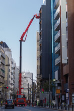 特殊なクレーンがゴンドラをつけて高所作業を行う。東京、赤坂5丁目の街の風景