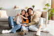 © Prostock-studio - Satisfied happy chinese teen daughter in casual clothes hugs young parents, sitting on floor in living room