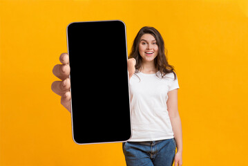 Poster - Cool mobile app. Woman showing cellphone with big blank screen, demonstrating space for your website design or ad