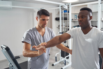 Wall Mural - Focused physiotherapist carrying out resisted isometric test