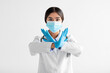 © Prostock-studio - Serious young indian lady doctor in uniform, gloves and protective mask show sign with hands, say no, cross arms