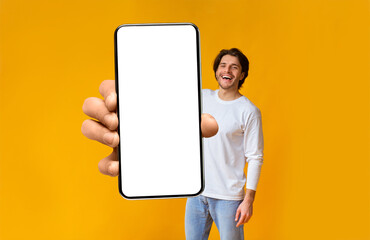 Poster - App ad. Excited man holding smartphone with white blank screen in hand close up to camera, mockup