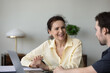 © fizkes - Happy skilled mature old businesswoman discussing online project on computer with young male colleague. Smiling 60s lady learning using software applications with teacher sitting together at table.