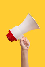 Megaphone In Woman Hands On A Yellow Background.