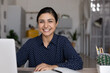 Happy mixed race Indian student girl looking at camera, smiling, working at laptop, studying from home. Ethnic distance employee, worker, businesswoman at table, desk with computer head shot portrait