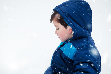 Wall Mural - Adorable boy in winter jacket surrounded with snow. Wintertime, kids activity