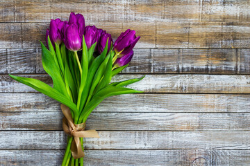 Wall Mural - Purple tulip, liliaceae on rustic desk. Cut flower bouquet on wood background