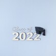 Class of 2022 wearing graduate hat on wooden number 2022 on grey background with copy space