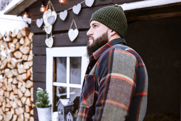 Wall Mural - handsome bearded man in stylish winter coat stands outdoor at porch of country house, winter spirit concept, decor for valentines day