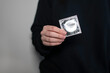 Woman hands holding condom package. A condom use to reduce the probability of pregnancy or sexually transmitted disease (STD). Safe sex and reproductive health concept.