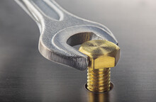 Wrench Tightens Brass Bolt In Steel Billet. Spanner, Bolt, Screw And Nuts.