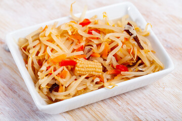 Pickled Chinese style vegetable salad from cabbage, bean sprouts, carrot and corn cobs served on white plate. Concept of vegetarian food