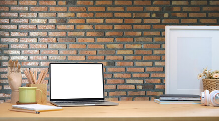 Wall Mural - Mock up computer laptop, supplies and empty frame on wooden table with brick wall.