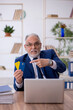 © Elnur - Old male employee holding credit card in the office
