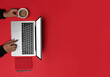 © Prathankarnpap - Above view woman holding coffee shop and laptop computer on red background.