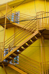 Wall Mural - Yellow metal staircase and brick wall building