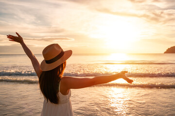 Young woman traveler walking and enjoying beautiful Sunset on the tranquil beach, Travel on summer vacation concept