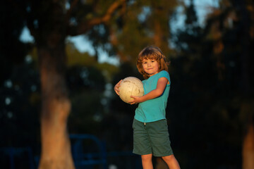 Wall Mural - Excited child boy kicking ball in the grass outdoors. Soccer kids, children play football. Active ball games.