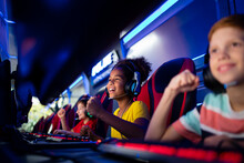 Group Of Cheerful Excited Children Or Professional Gamers Playing Video Games On Computer In Game Room.