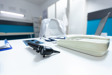 Bright empty doctor office equipped with professional medical instruments ready for clinical examination. Hospital room with nobody in it having otoscope and landline on desk table. Medicine concept