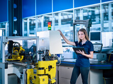 Engineer With Tablet PC Standing Near Machine In Industry