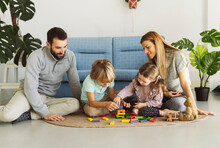 Brother And Sister Playing Toy Blocks With Parents In Living Room
